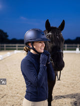 Rider wearing a navy Samshield Miss Shield 2.0 Cosmic Night helmet putting on gloves at a floodlit arena at dusk (AI)