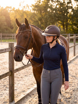 Rider wearing a brown Samshield Miss Shield 2.0 Crystal Fabric Gold helmet leading her horse along the fence