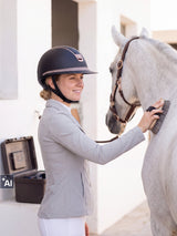 Rider wearing a Samshield Miss Shield 2.0 Rose Gold helmet grooming her grey horse (AI)