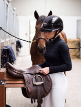 Rider wearing a Samshield Miss Shield 2.0 Shadowglossy Sparkling helmet lifting a saddle from the rack (AI)