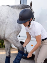Rider wearing a Samshield Miss Shield 2.0 Sparkling 300 Swaro helmet removing her horse's travel boots
