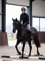 Rider wearing a Samshield Shadowmatt 2.0 Crystal Fabric helmet trotting over ground poles in the indoor arena